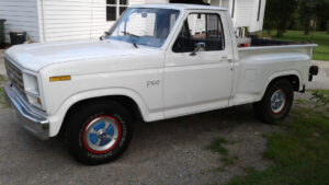 A clean white 1986 Ford F150 regular cab pickup with 15-inch factory-style aluminum wheels, featured as Entrant #33 in the 2020 Virtual Truck Show.