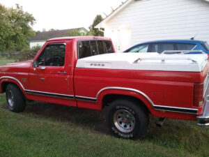 A red 1986 Ford F150 regular cab with a 5.0L 302 V8 engine and original red patina, featured as Entrant #34 in the 2020 Virtual Truck Show.