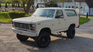 A white 1985 Ford Bronco XLT with a 4-inch lift and black wheels, owned by Matt Wood in the UK and featured in the 2020 Virtual Truck Show.