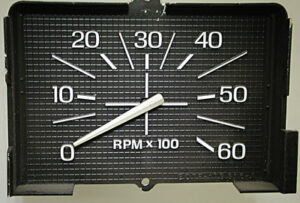 A technical illustration showing the face of a Ford tachometer, the three mounting/electrical studs on the rear, and its connection to the cluster's printed circuit board.