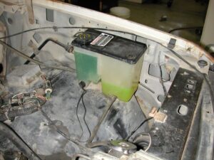 Comparison photo showing the bottom of early and late style Ford truck coolant reservoirs with different mounting pins circled for modification.