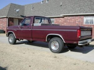 A 1980-1986 Ford F-Series truck undergoing restoration, showing the original factory white wagon wheels and later aluminum wheel upgrades.