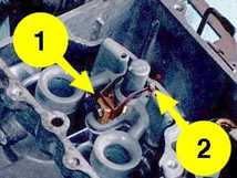 A technical breakdown of carburetor jetting for Ford 300, 302, and 351W engines, including a photo of the variable high-speed bleed system (metering rods) on a Motorcraft 2150.
