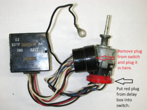 A side-by-side comparison of a black Ford wiper delay governor module with its wiring harness and a chrome-knobbed dashboard wiper switch.