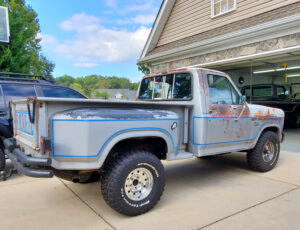 Silver 1985 Ford F150 XL Flareside 4x4 with blue stripes and black wheels, an entrant in the 2020 Virtual Truck Show.
