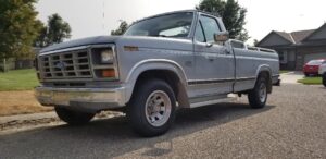 Silver 1986 Ford F150 XLT Lariat regular cab with a tool box and bed rails, an entrant in the 2020 Virtual Truck Show.