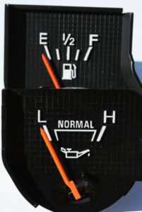 NOS Ford Bullnose fuel gauge and oil pressure gauge face-to-face comparison showing original fluorescent orange needle color variation