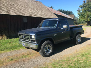 A restored Medium Blue Metallic 1985 Ford F150 Flairside 4x4 with a wood-plank bed and fuel-injected 302 V8, featured in the 2020 Virtual Truck Show.