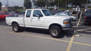 A white 1995 Ford F150 Super Cab with aftermarket alloy wheels and a toolbox, entered as #26 in the 2020 Virtual Truck Show.
