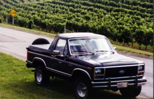 A charcoal and silver 1986 Ford Bronco XLT with a 1995 Lightning 5.8L engine, featured as Entrant #23 in the 2020 Virtual Truck Show.