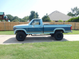 A 1985 Ford F250 XLT Lariat 4WD known as Big Blue, featuring a front winch bumper and a heavy-duty Dana 60 straight axle conversion.